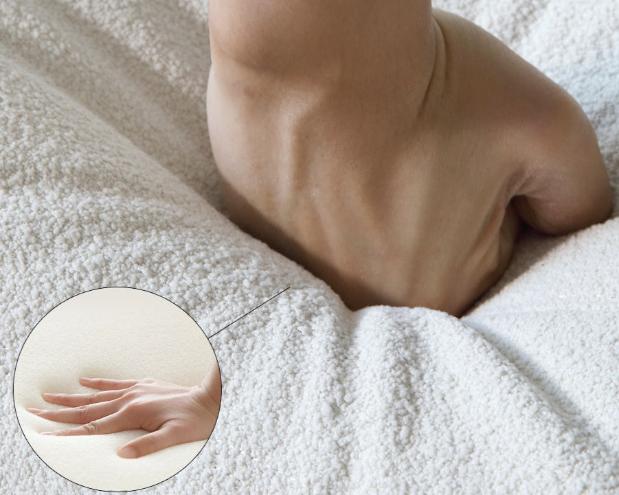 Person pressing on the seat cushion of a white sofa to show its softness.