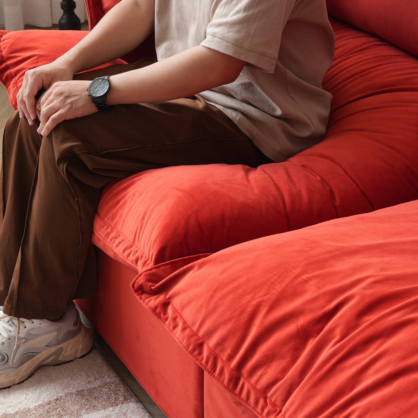 Person sitting on a sofa cushion of a red sofa to show its softness and deepness