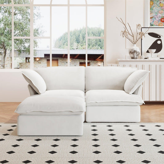 A white chaise lounge loveseat linen sectional sofa with a modular design and a storage ottoman, placed on a patterned rug in a bright living space.