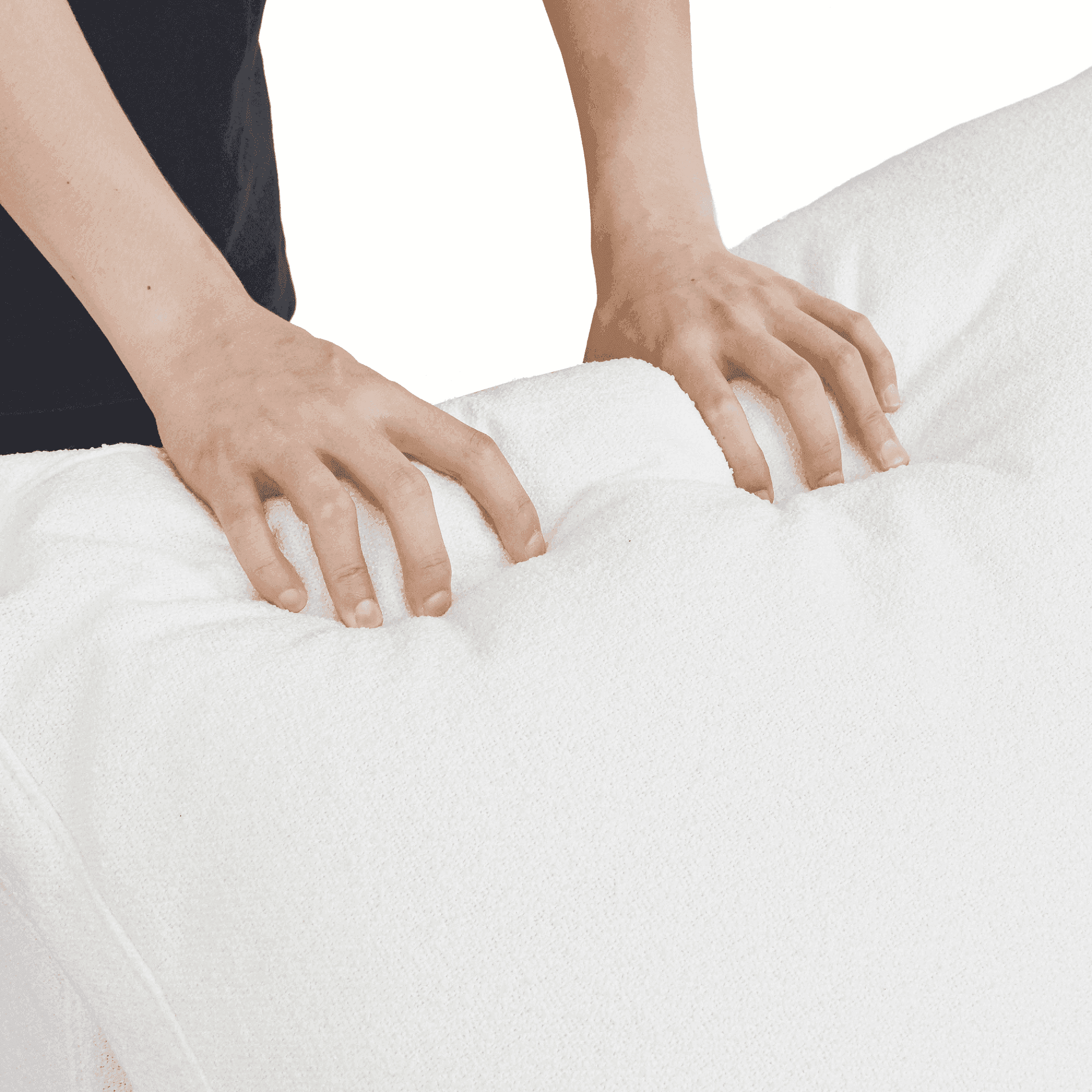 Person squishing a backrest cushion of a white sofa to show its softness