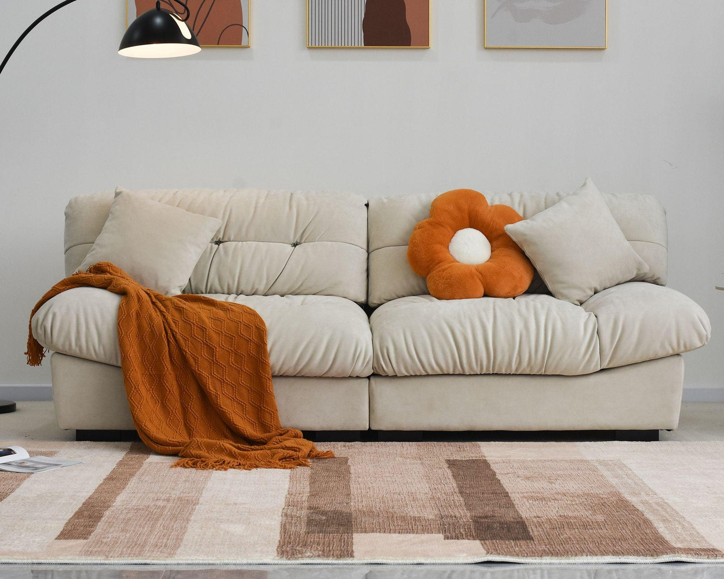 An 89-inch beige microfiber suede sofa with an orange decorations; solid hardwood frame, presented in a living room setting with minimalistic decor.