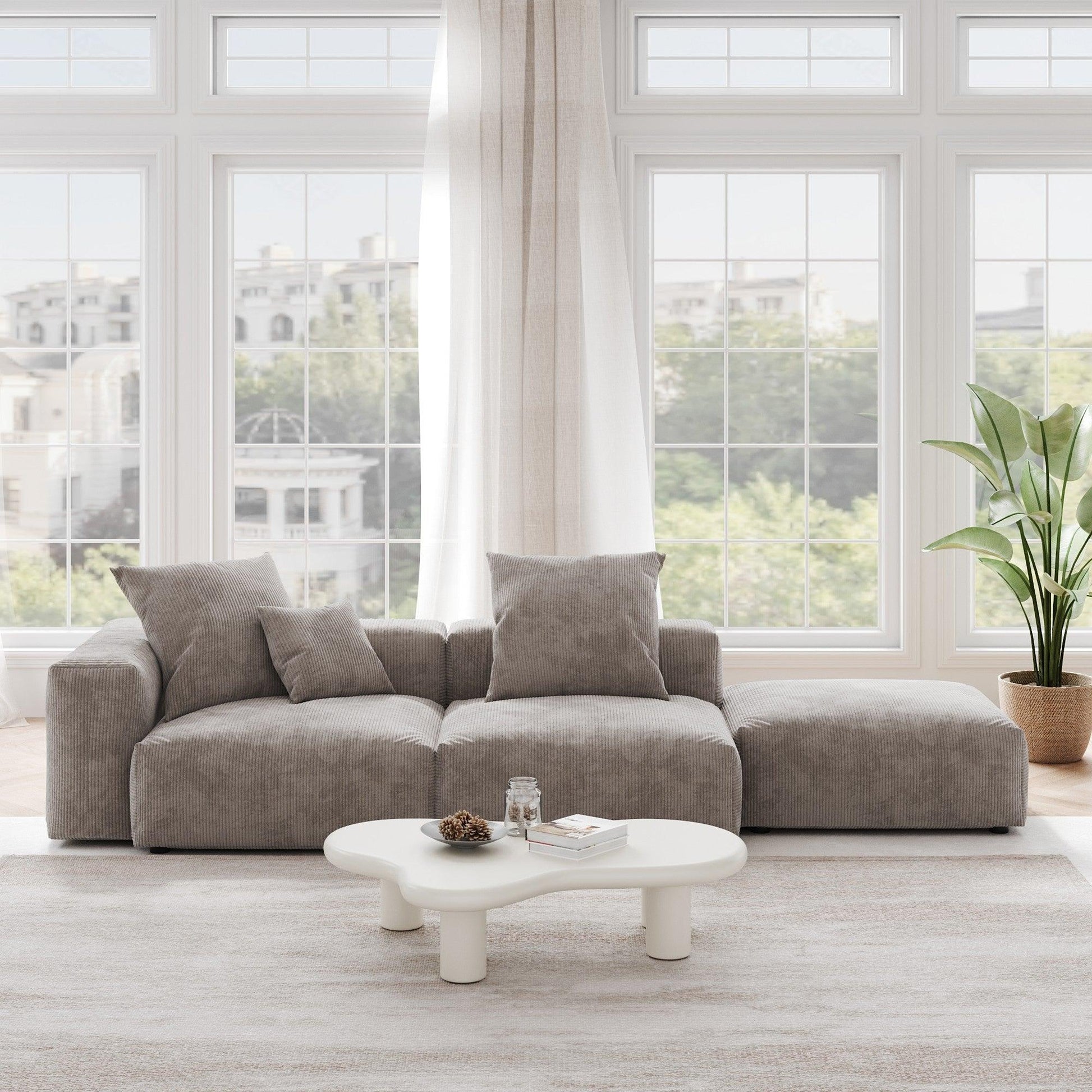 A brown corduroy 3-seat sectional lounger sofa with detachable armrests and removable covers, positioned in a bright room with large windows.