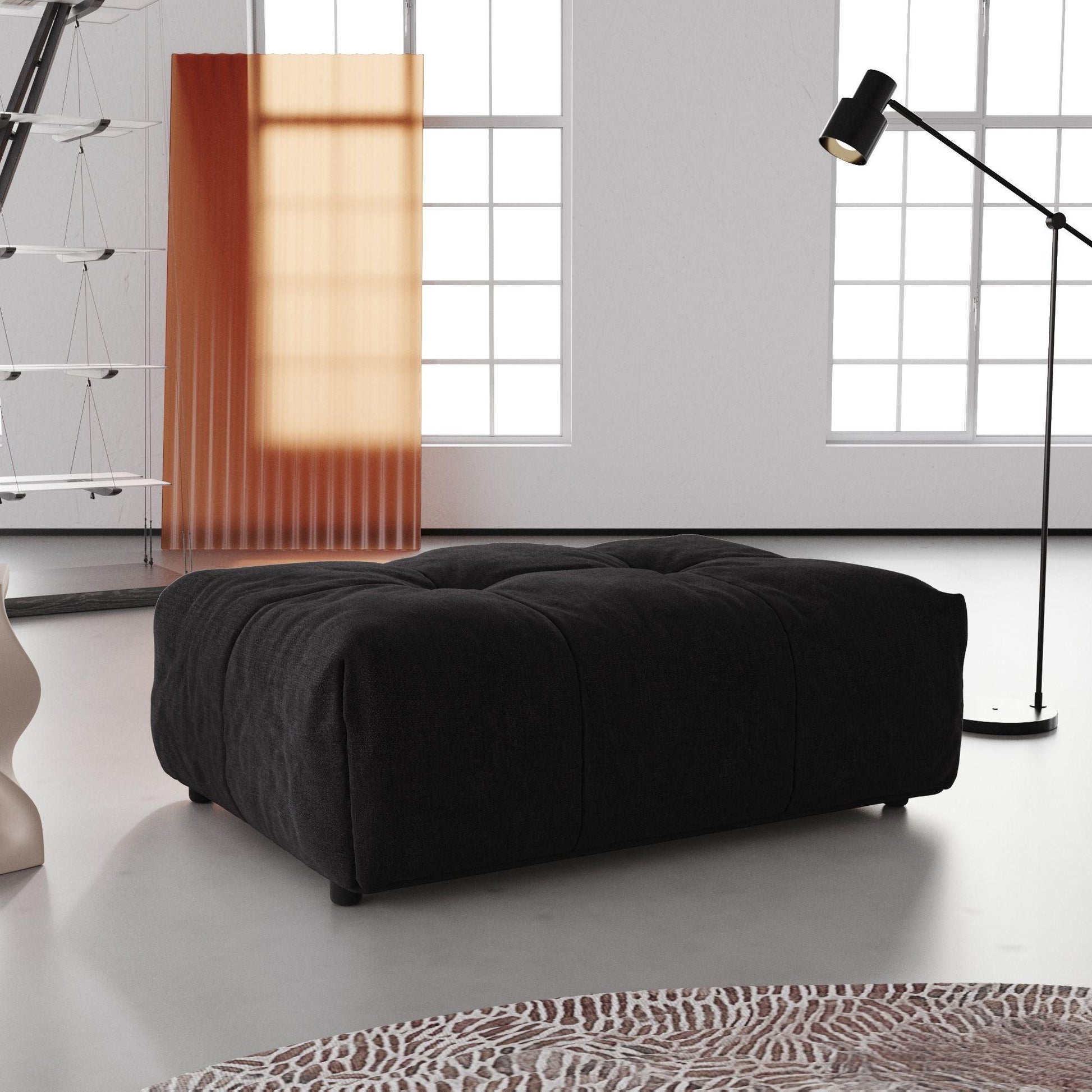 A black linen ottoman in a modern living room setting, with a low-profile and cushioned top.