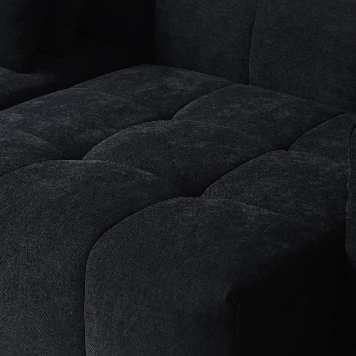 Close-up of a seat of a black tufted sofa