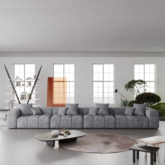 Modern living room with a large gray 4-seater sofa, coffee table, and decorative elements.