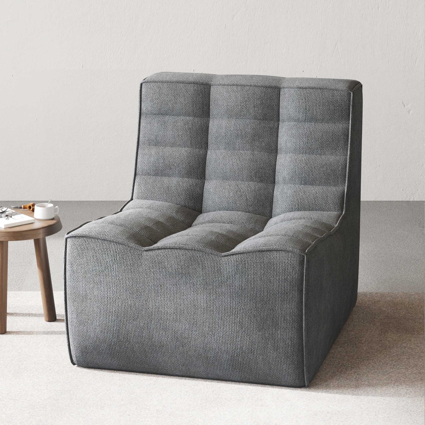 A black chenille accent chair with a minimalist design in a studio light