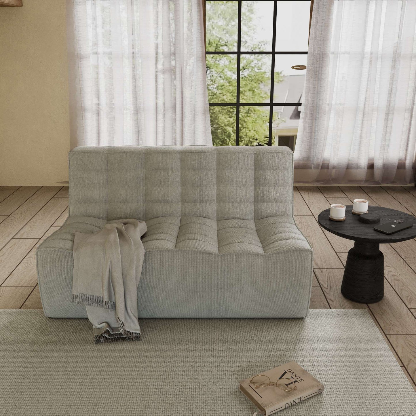 A light gray cotton-linen 2-seater sofa with an ergonomic caterpillar design, placed in a room with a window, curtains, a small round table, and a book on the floor.
