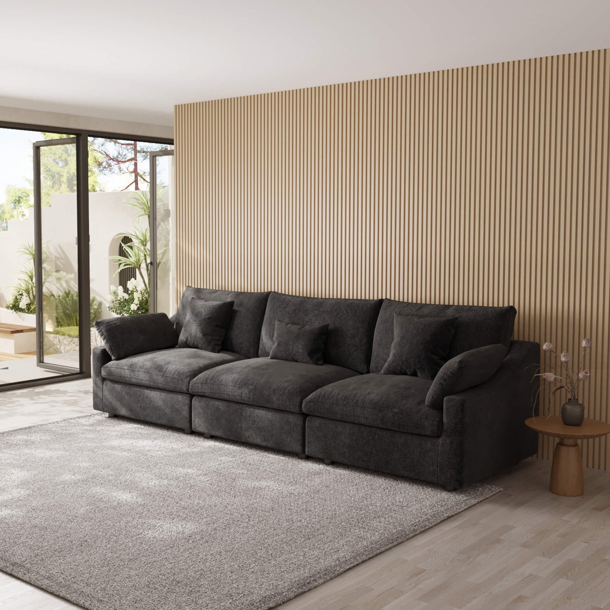 Black 3-seater sofa in a modern living room with a striped wall and large windows.