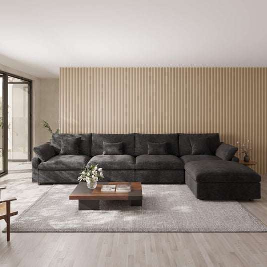 Black sectional 5-seat sofa with ottoman in a modern living room with a coffee table and decorative items.
