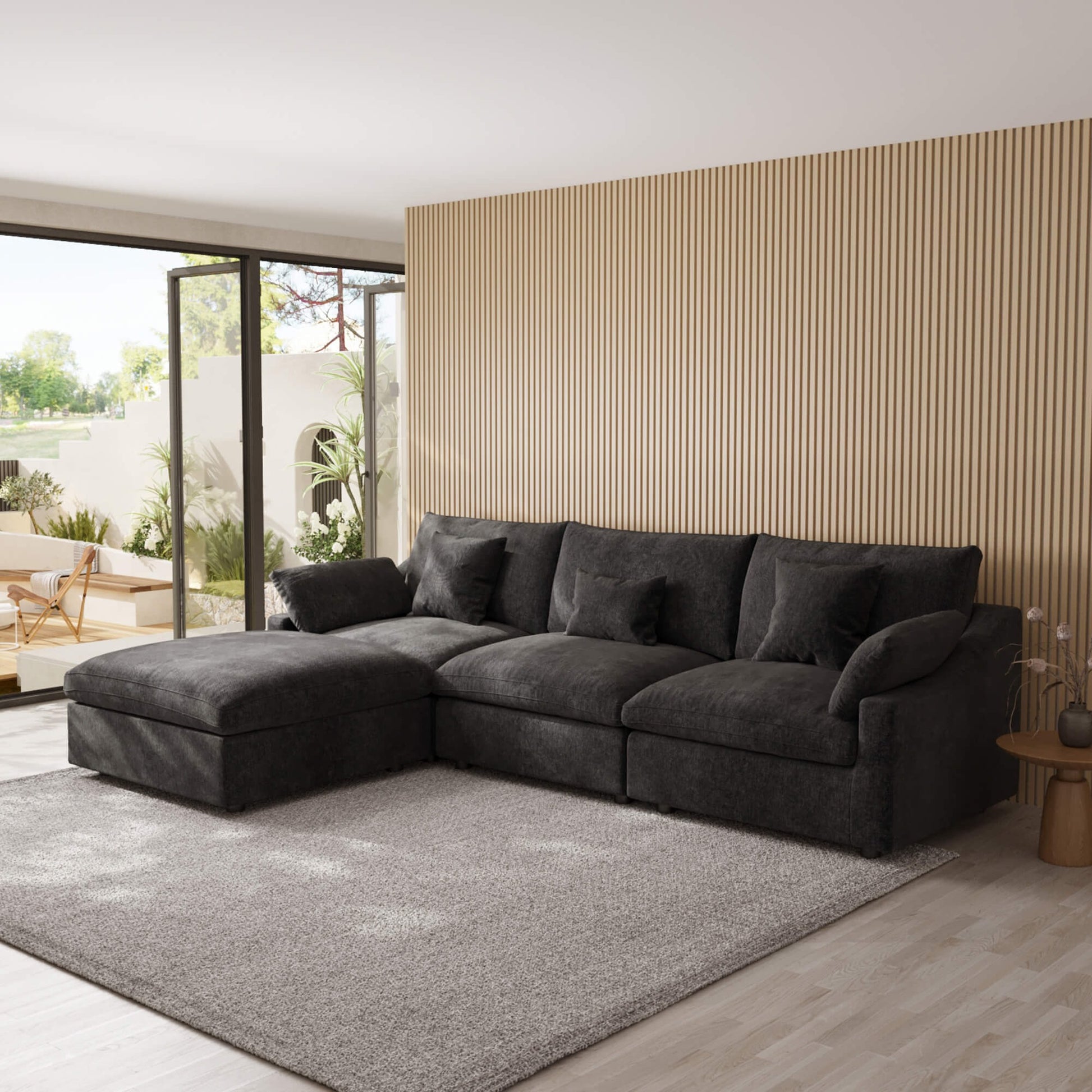 Black L-shaped sectional sofa in a modern living room with a striped wall and patio doors.