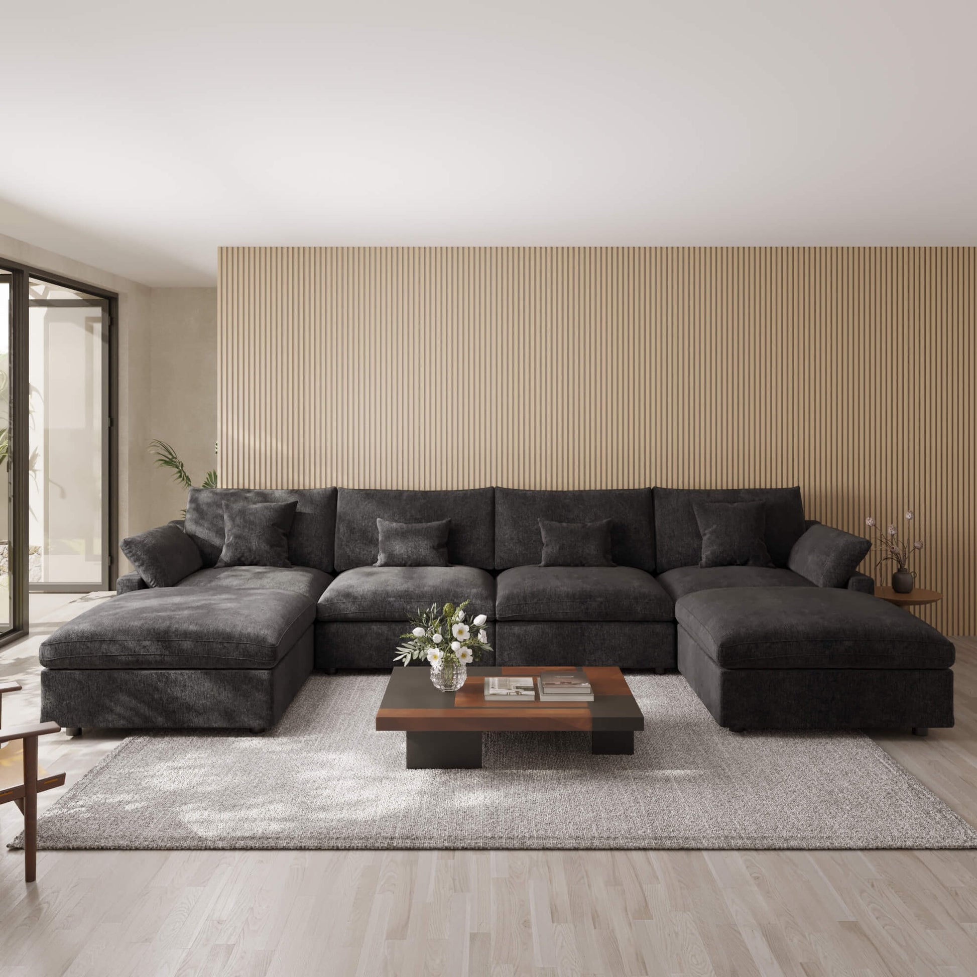 Black U-shaped sectional sofa in a modern living room with a coffee table and decorative items.