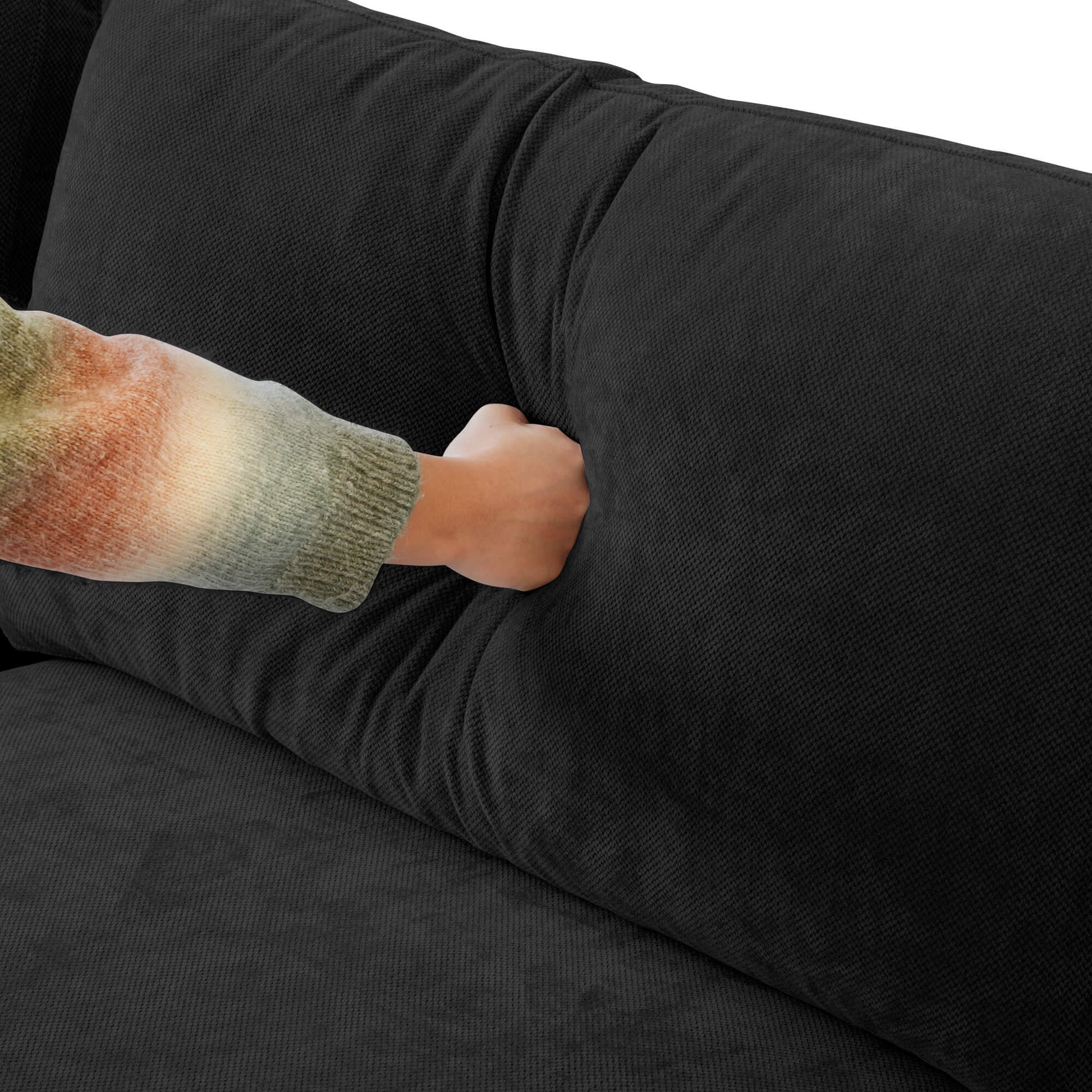 Person pressing on a backrest cushion of a black couch