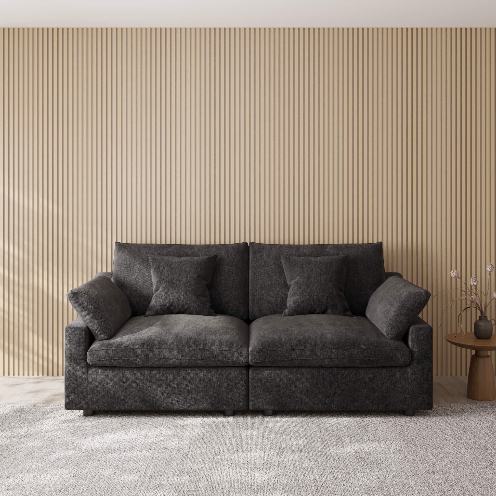 Black loveseat couch in a room with a striped wall and small table.