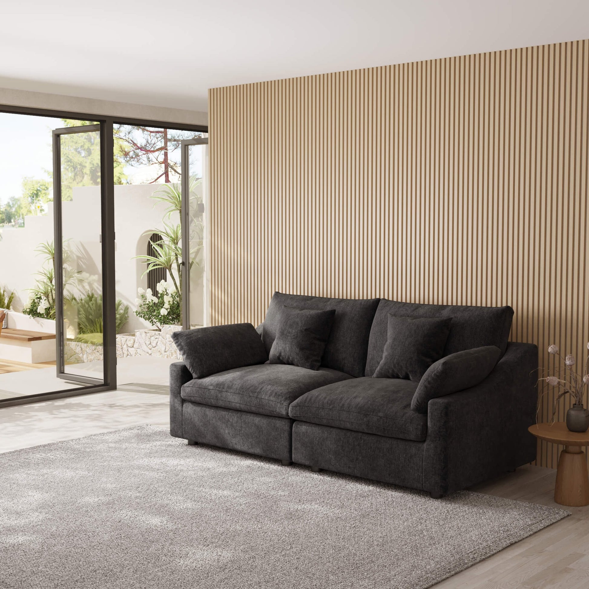 Black loveseat sofa in a modern living room with a striped wall and sliding glass door.