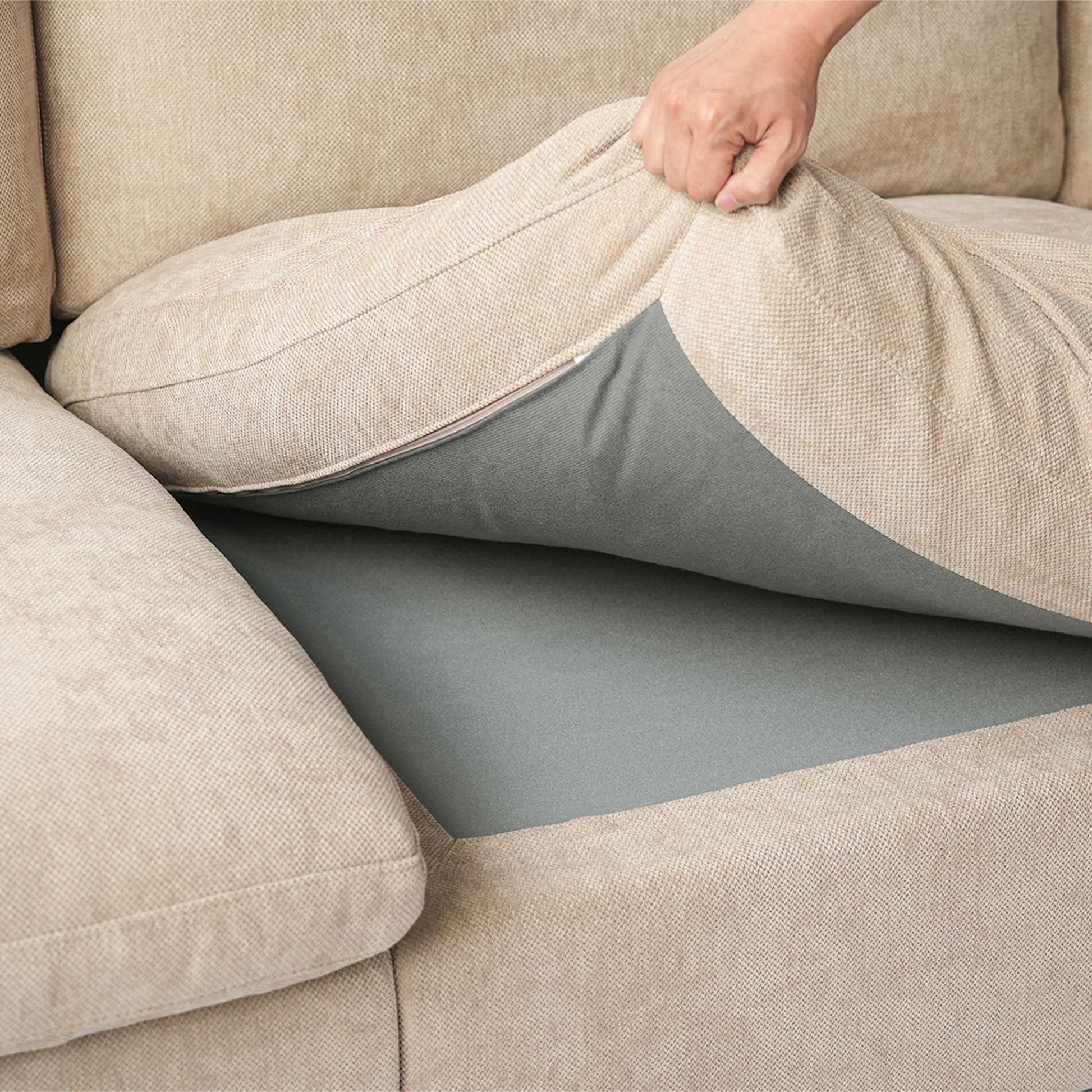 Person adjusting a khaki seat cushion over a sofa section.
