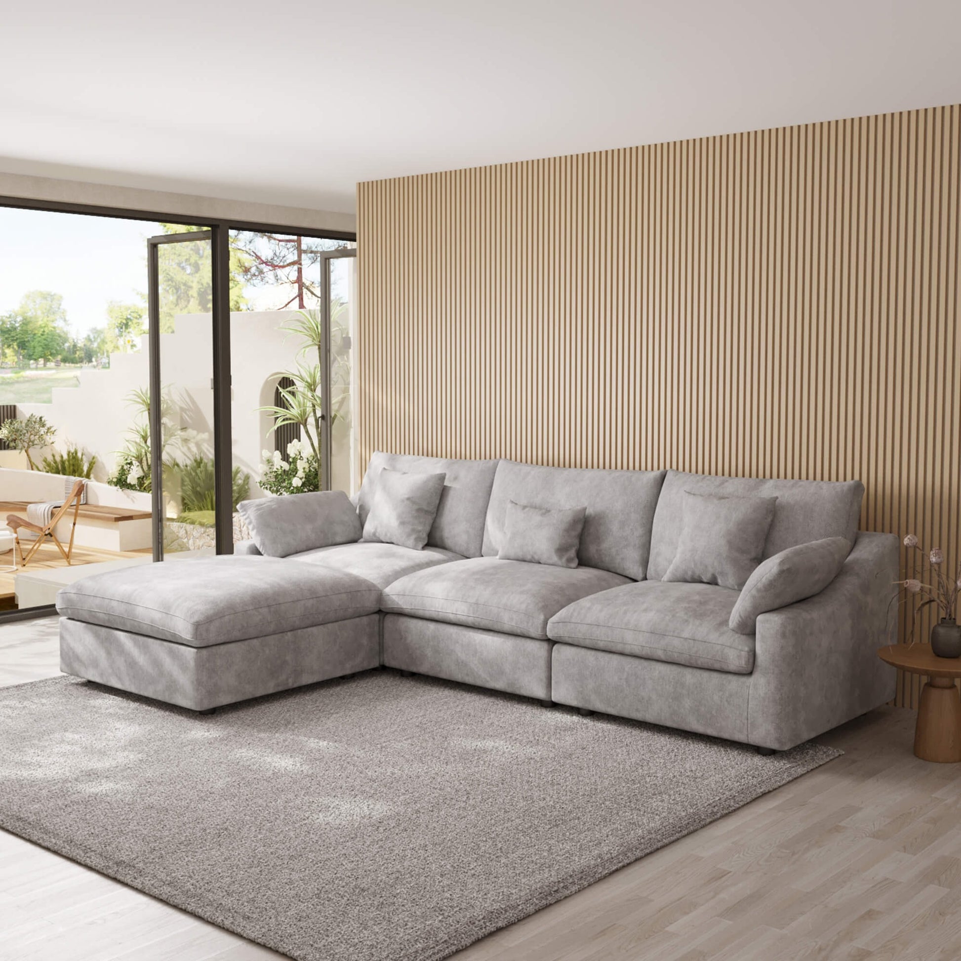 Light gray L-shaped sectional sofa in a modern living room with wooden floor and striped wall.