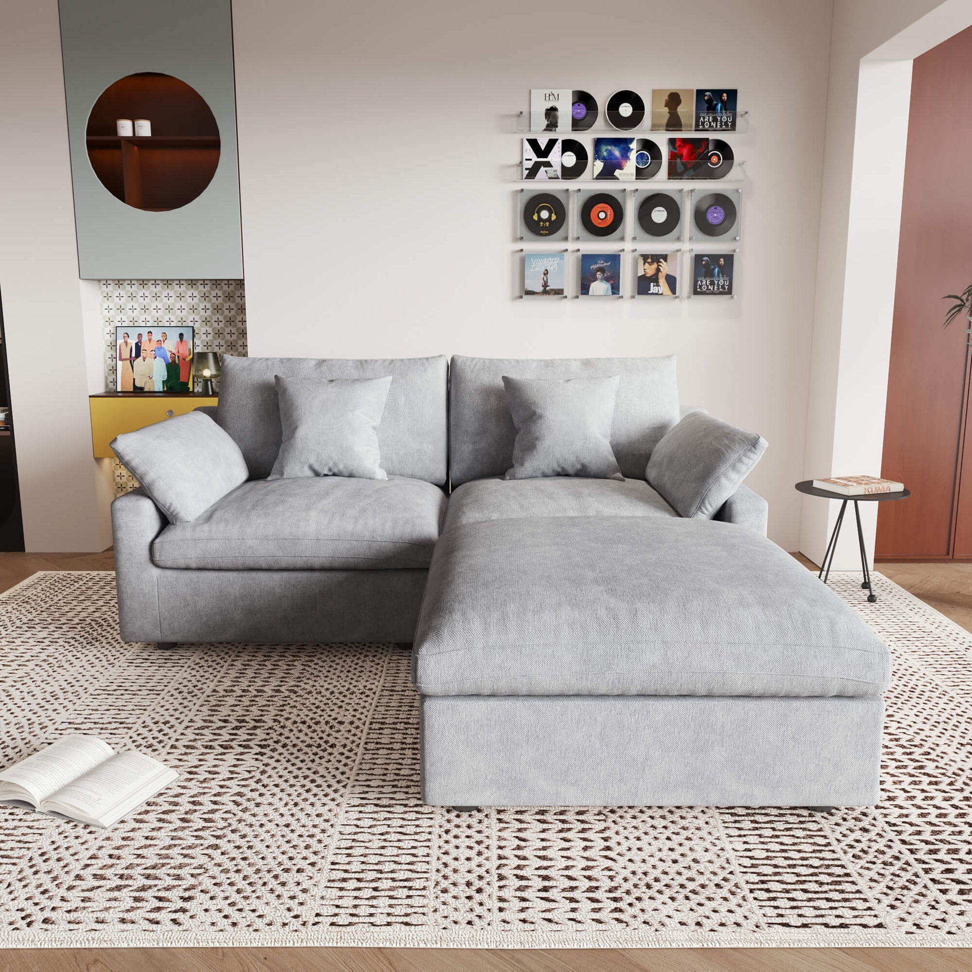 A light gray linen loveseat with ottoman, featuring a washable cloud design, placed on a patterned rug in a room with a record collection on the wall.