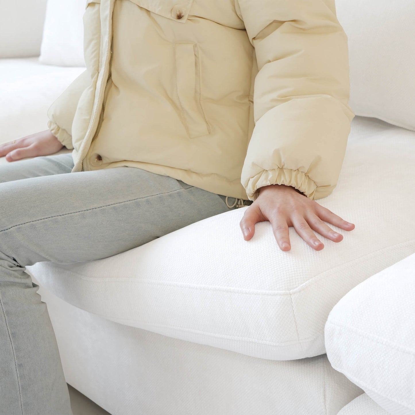 Person sitting on a seat cushion of a white sofa