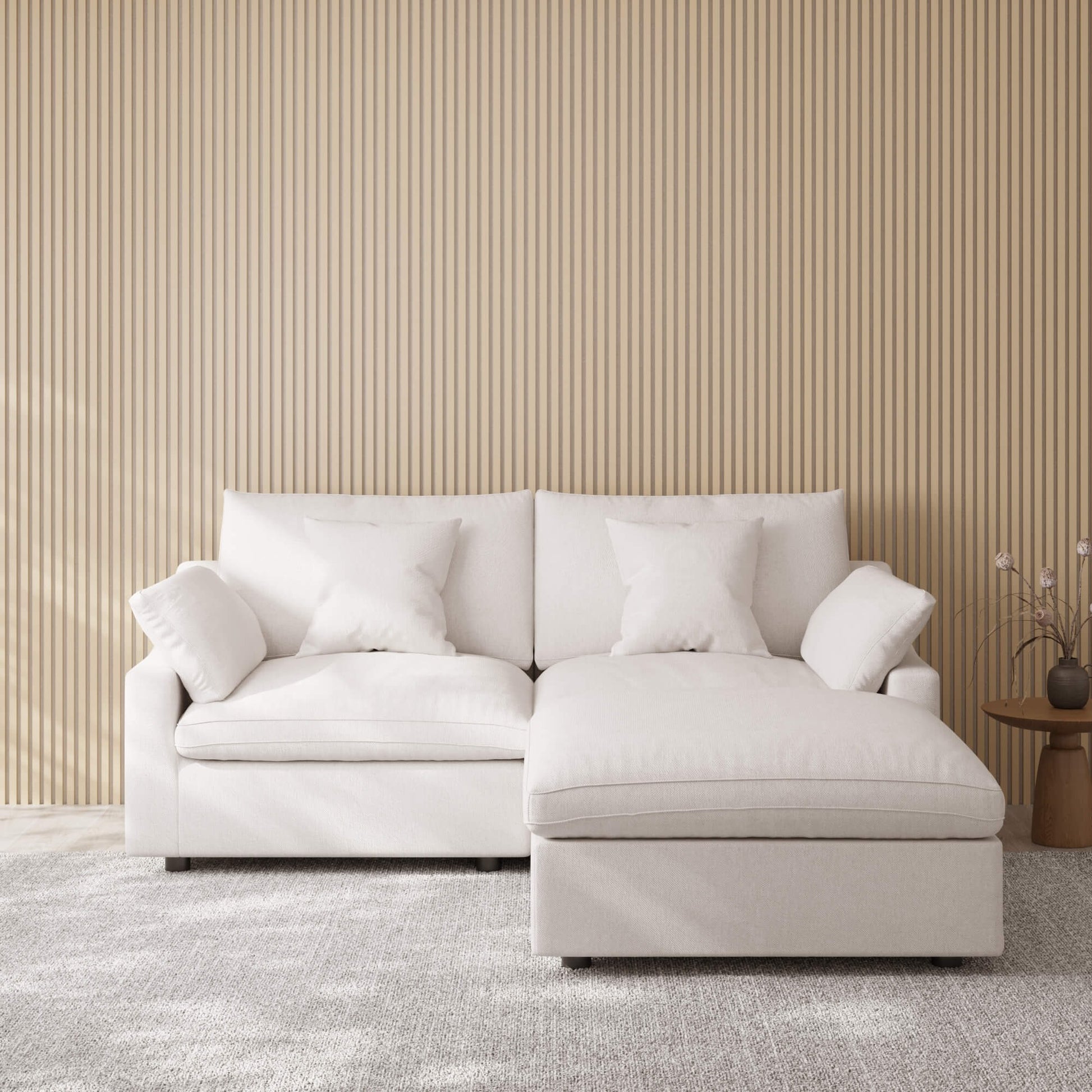 White sofa with a chaise lounge against a beige wall.