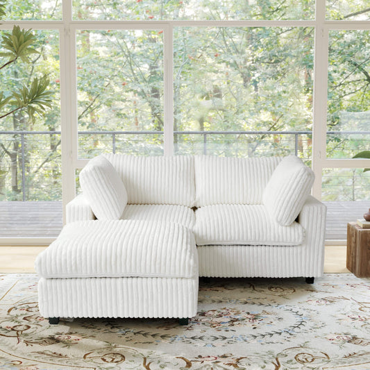 Beige faux rabbit fur sectional loveseat sofa with ottoman in a room with large windows and greenery outside.