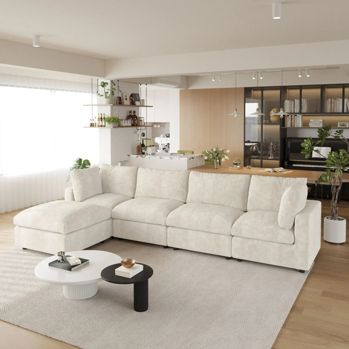 Modern living room with a beige L-shaped 5-seater sectional sofa, coffee table, and kitchen in the background.