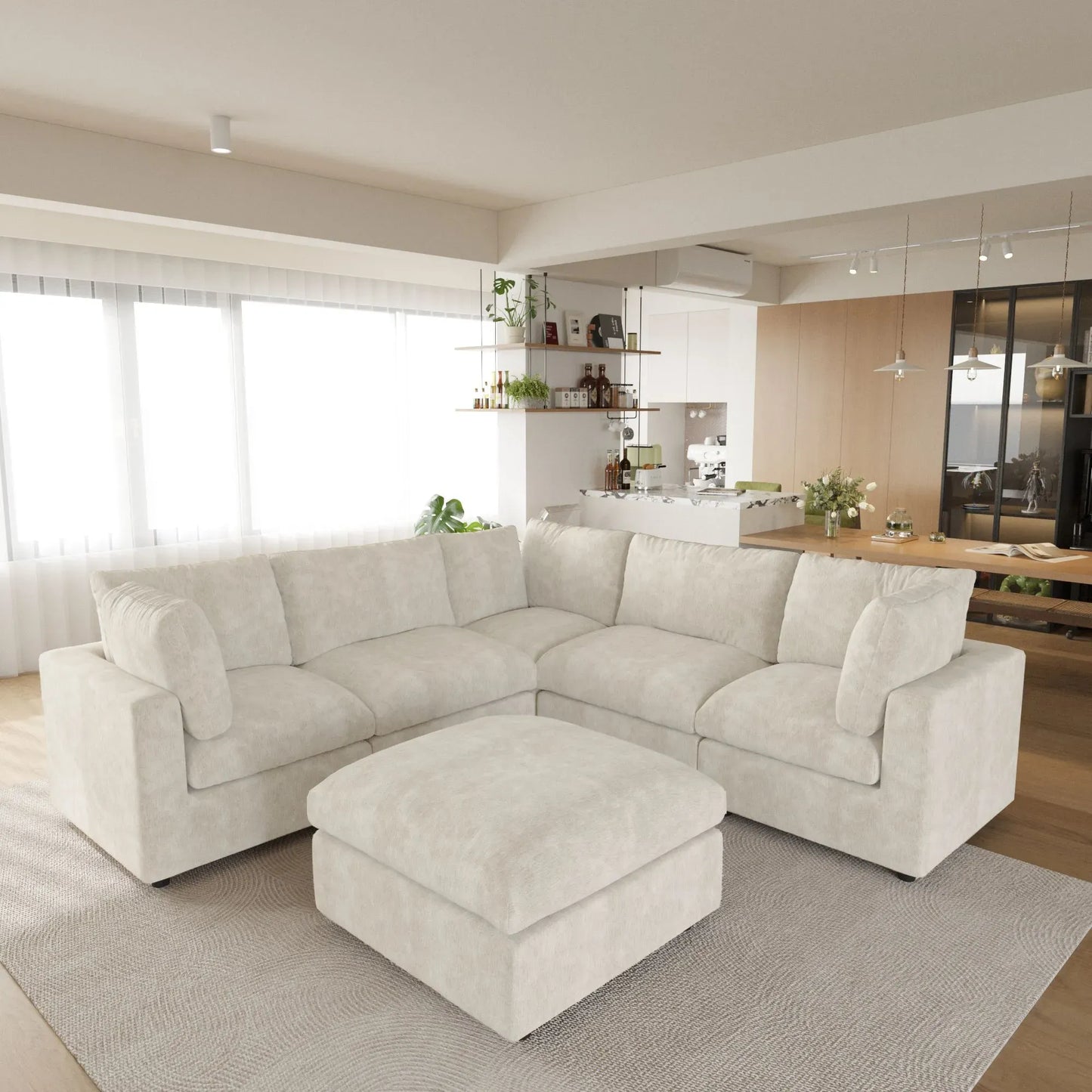 Beige V-shaped corner sectional sofa with ottoman in a modern living room with kitchen in the background