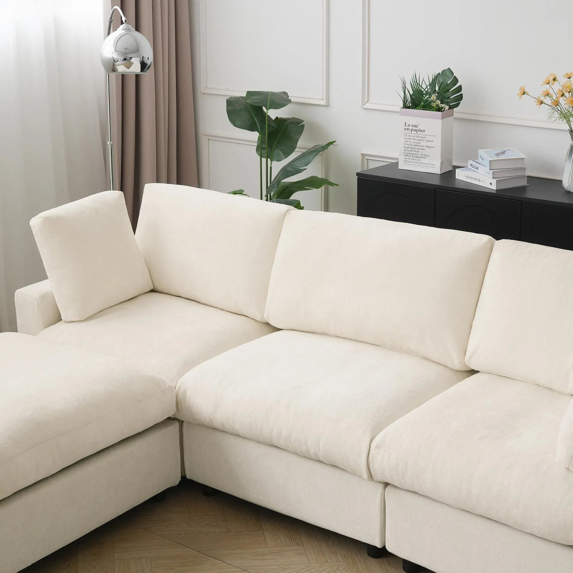 Beige sectional sofa in a living room setting with decor elements.