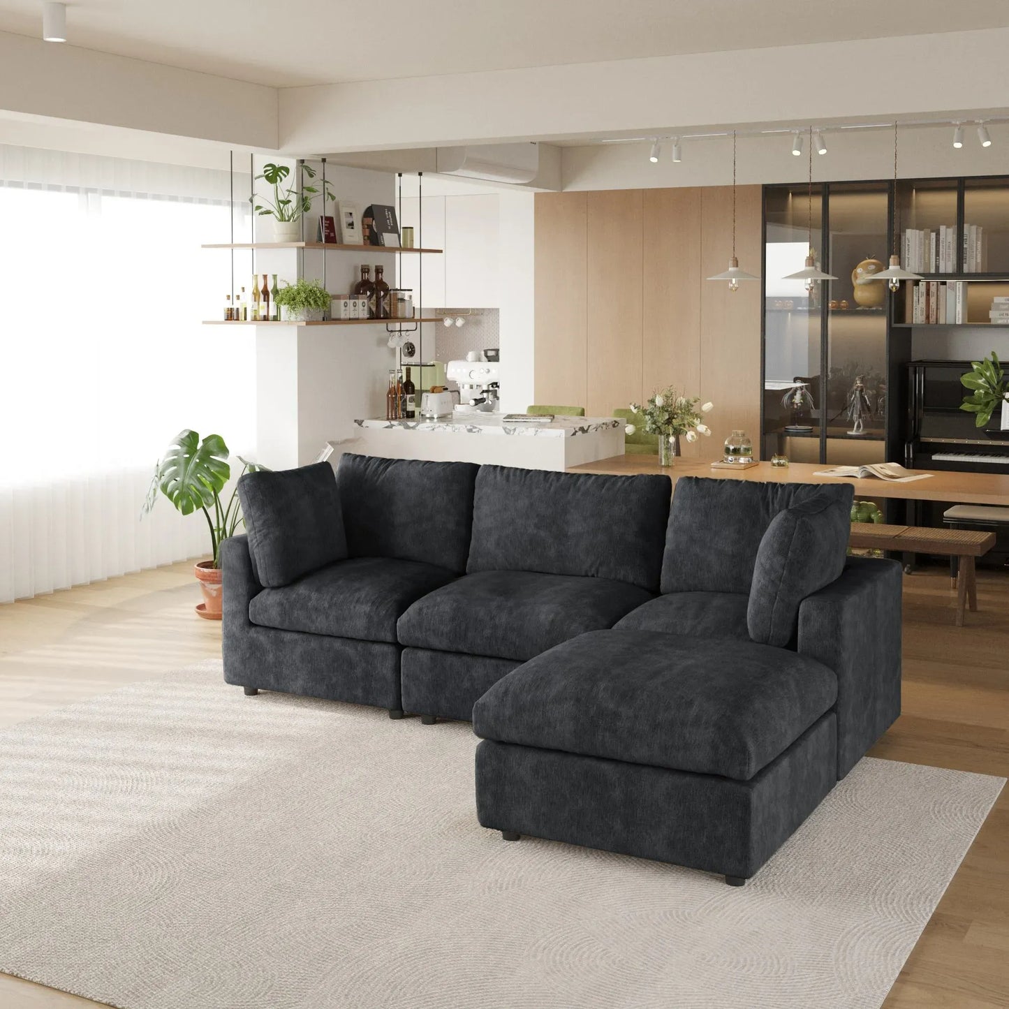 Black L-shaped 4-seater sectional sofa in a modern living room with a kitchen in the background.