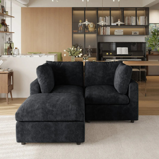 Black sectional sofa in a modern living room with a kitchen in the background.