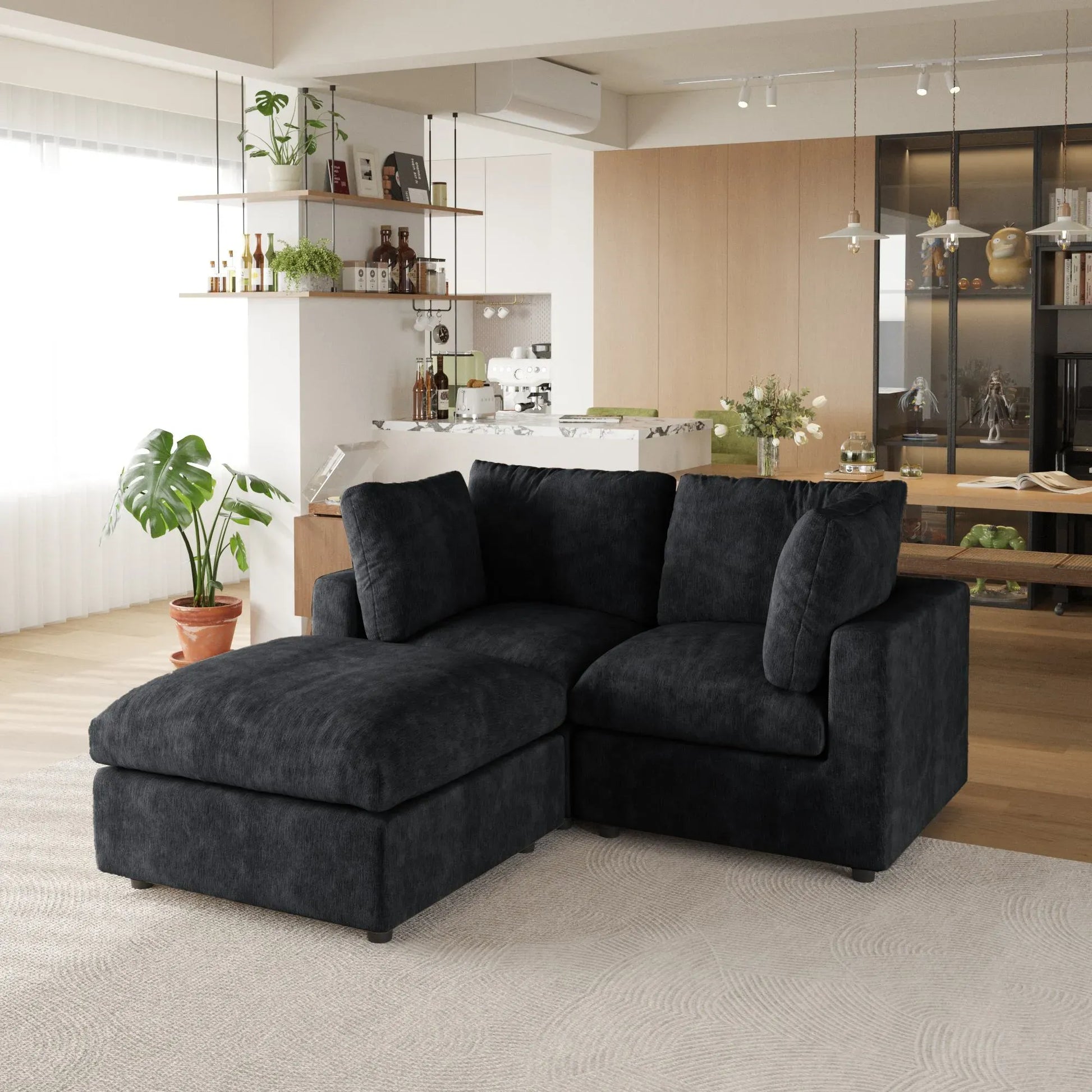 Black sectional sofa in a modern living room with kitchen in the background