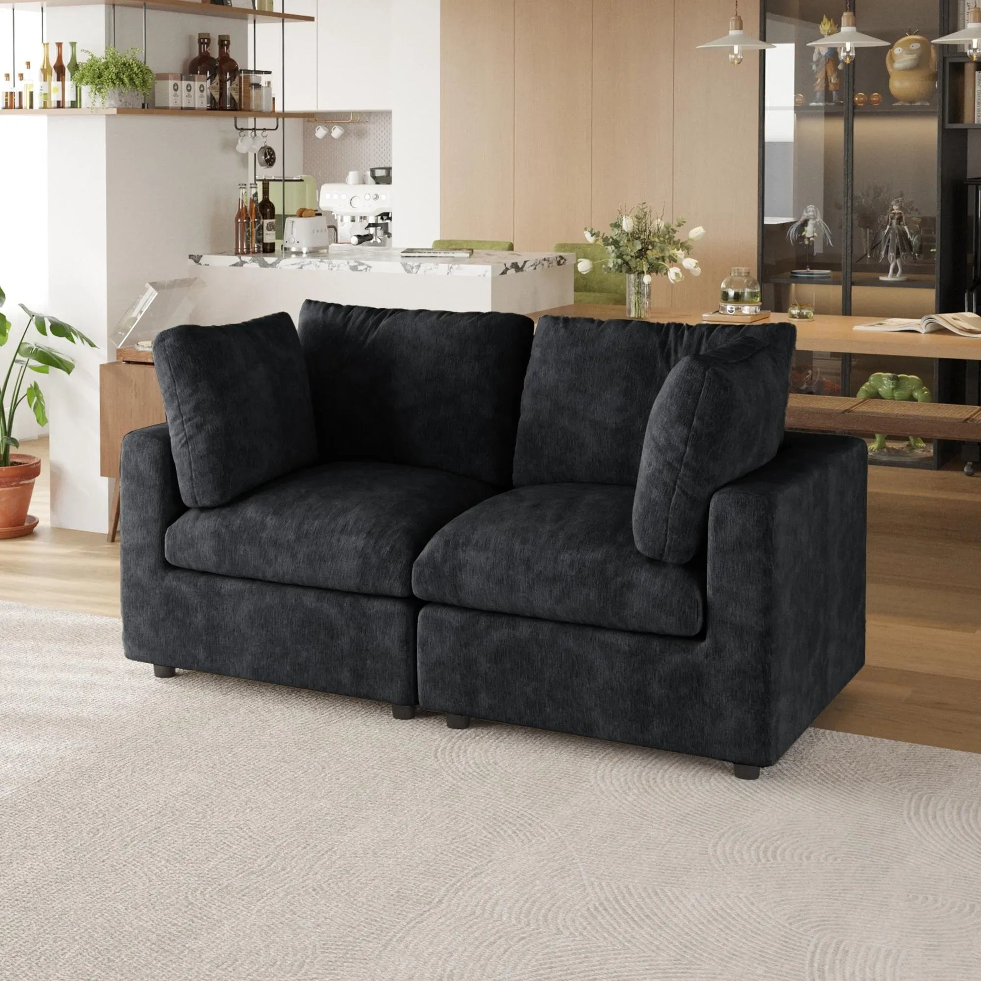 Black sofa in a living room with a kitchen in the background