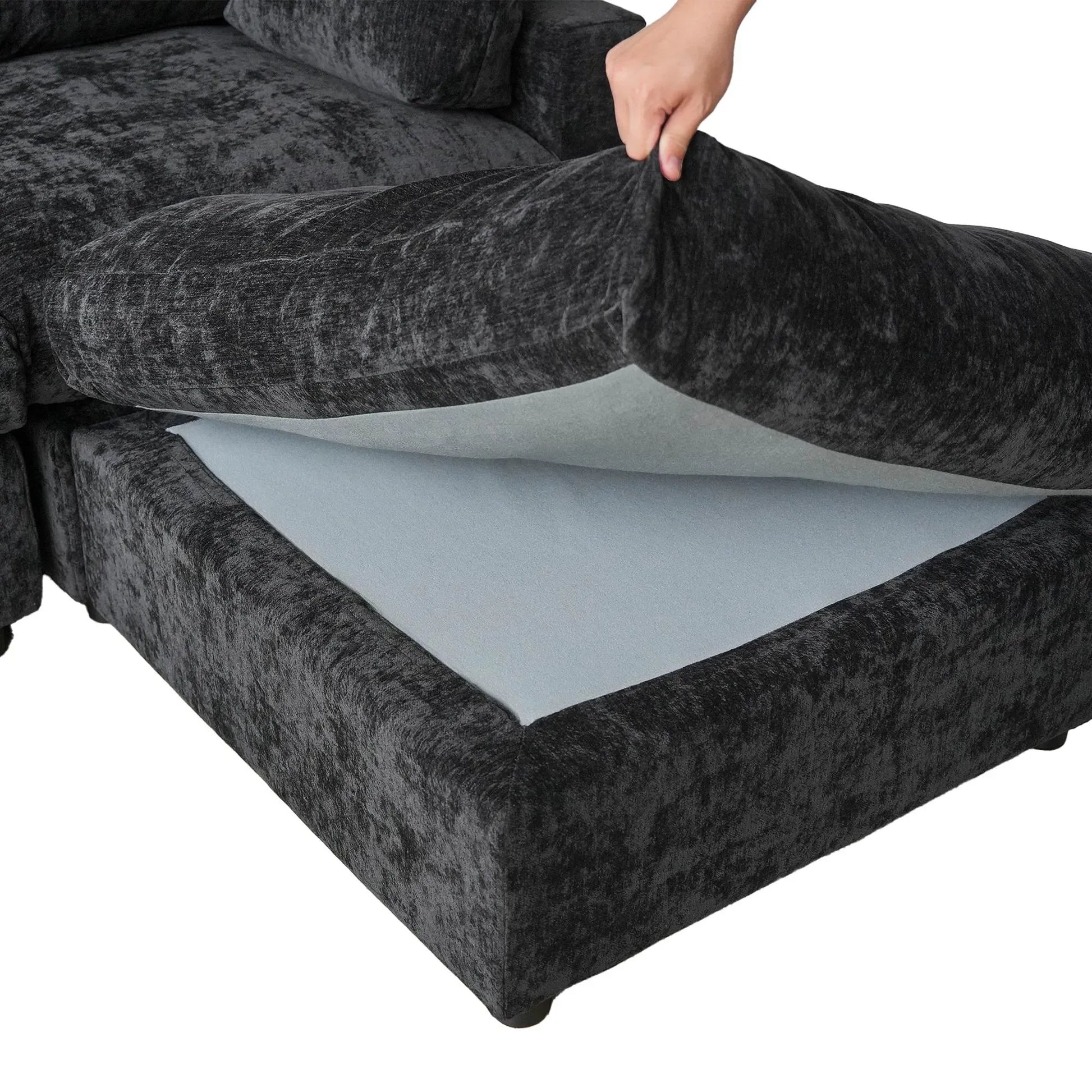 Person removing a seat cushion from a black sofa