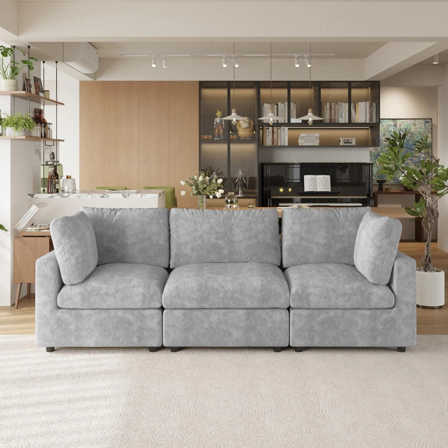 Gray sectional 3-seater sofa in a modern living room with bookshelves and decor.