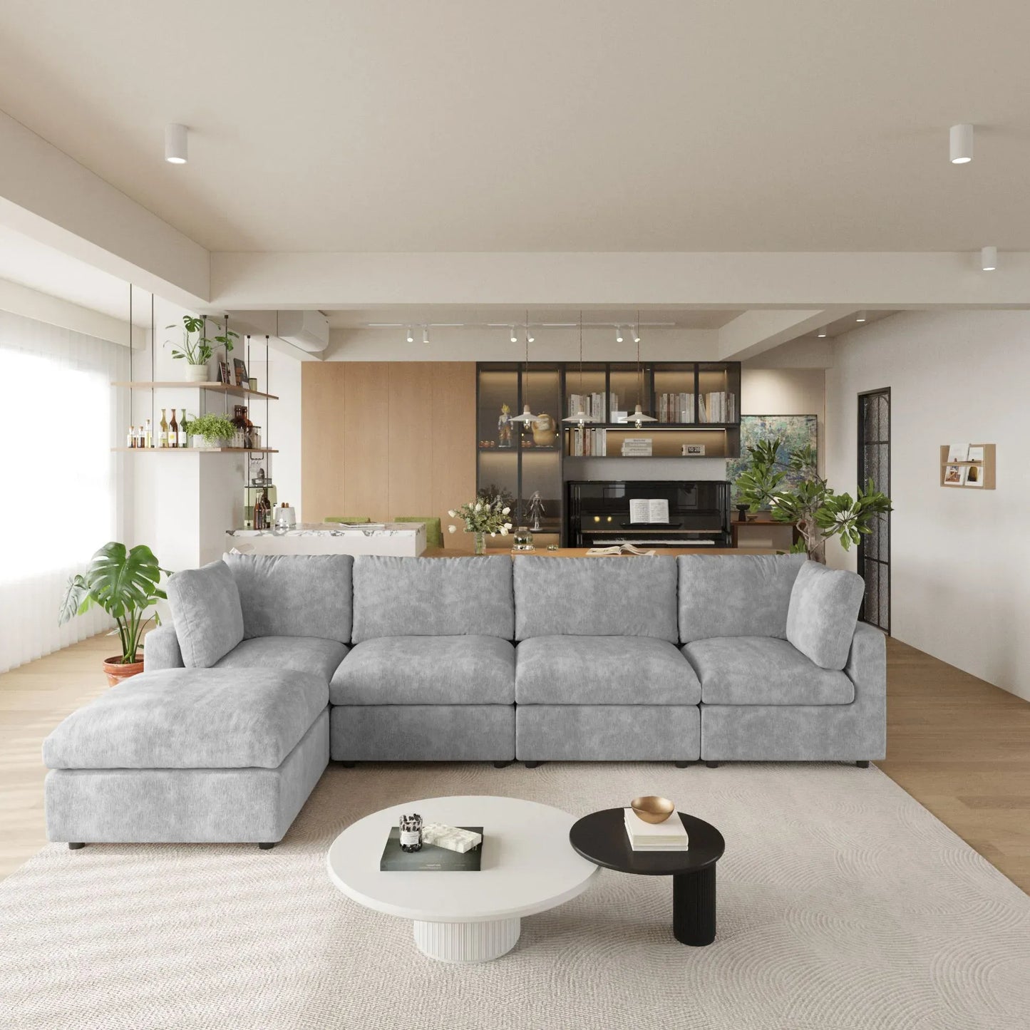 Modern living room with a gray L-shaped 5-seater sectional sofa, coffee table, and kitchen in the background.