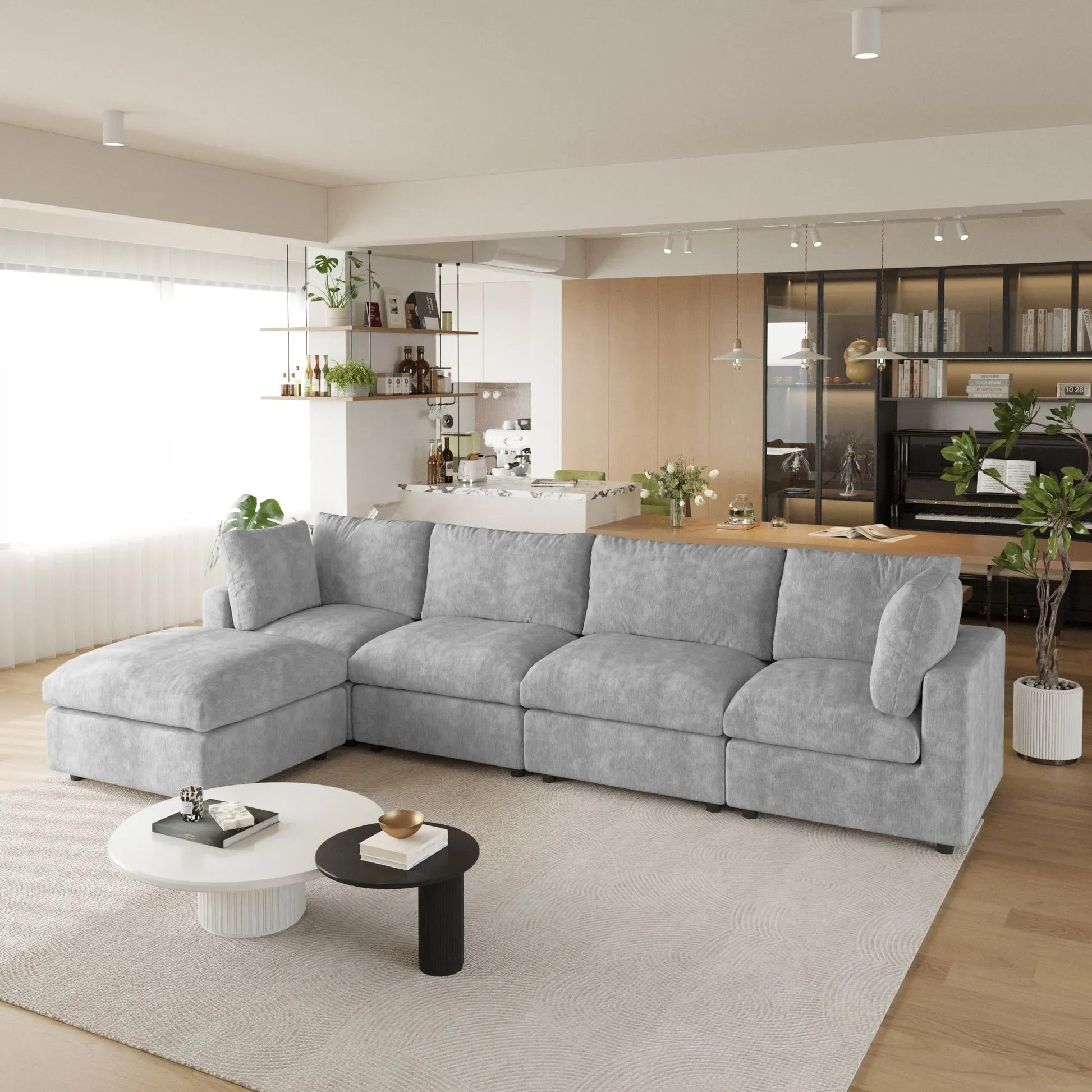 Gray L-shaped 5-seater sectional sofa in a modern living room with a kitchen in the background.