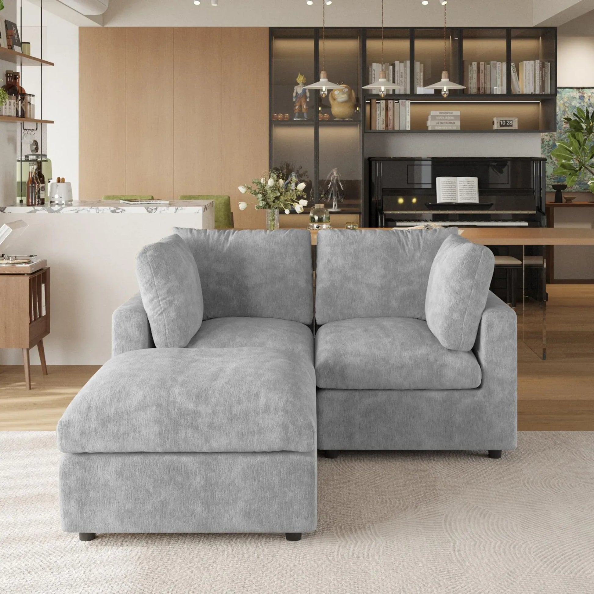 Gray sectional sofa in a living room with a piano and bookshelves.