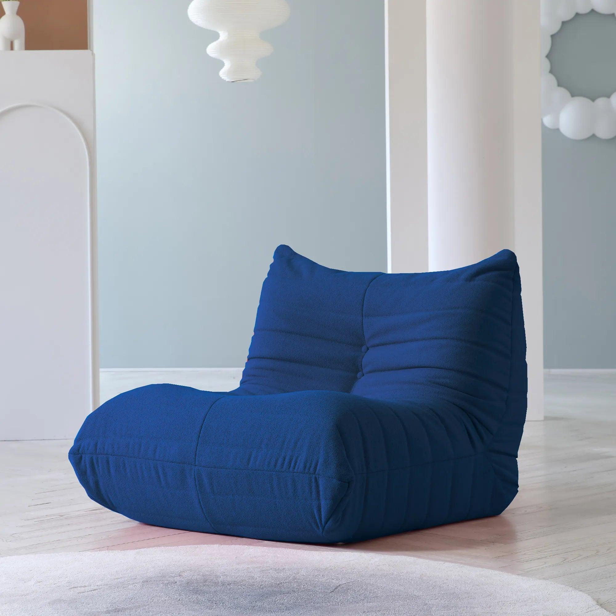 A distinctive blue caterpillar-shaped floor armchair placed on a wooden floor in a room with light blue walls.