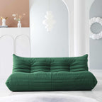 A distinctive green caterpillar-shaped 3-seater Togo sofa placed on a white floor in a room with light-colored walls and a painting in the background.