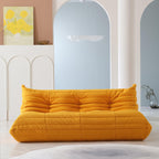 A distinctive yellow caterpillar-shaped 3-seater Togo sofa placed on a white floor in a room with light-colored walls and a painting in the background.