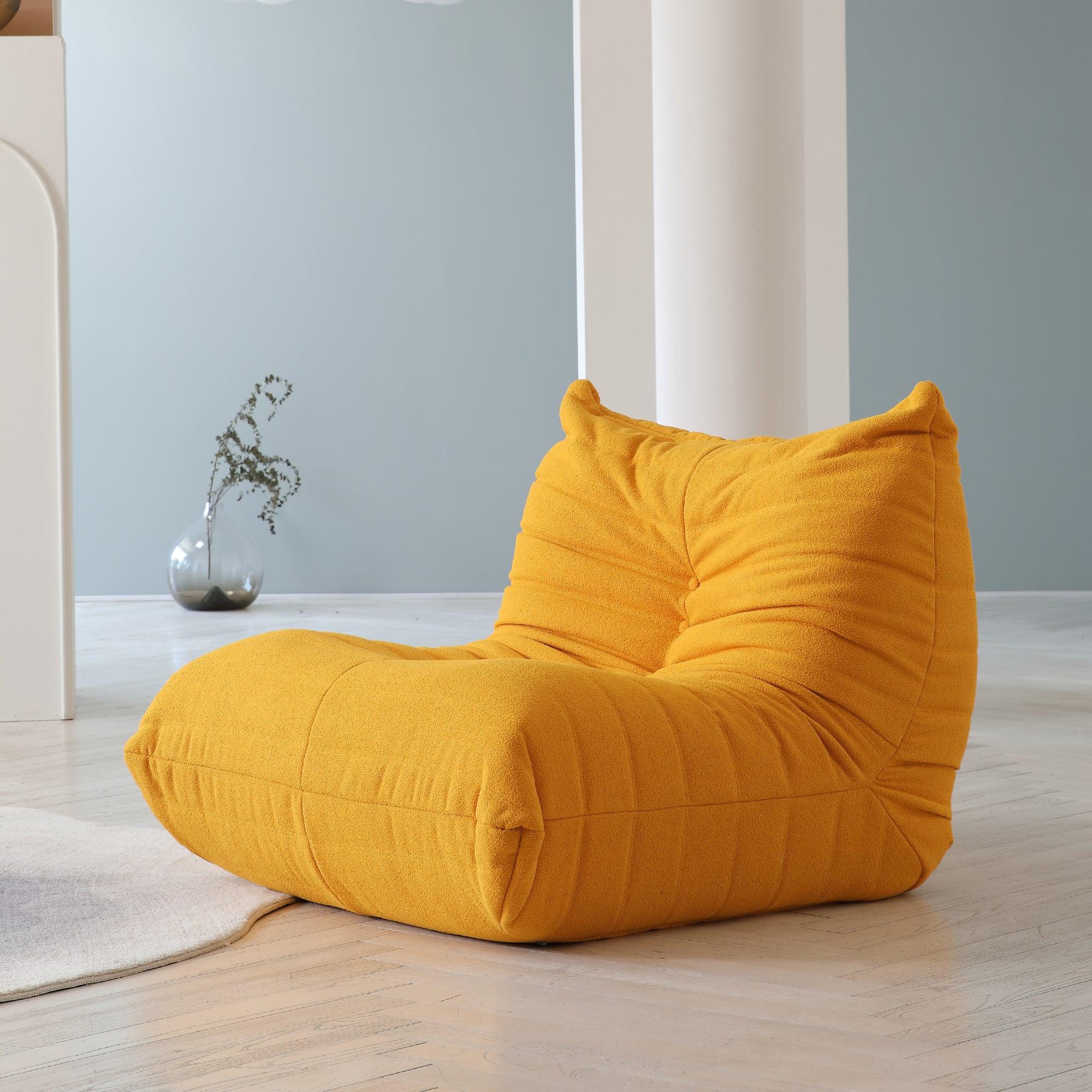 A distinctive yellow caterpillar-shaped floor armchair placed on a wooden floor in a room with light blue walls.