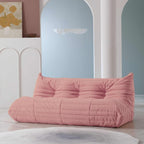 A distinctive pink caterpillar-shaped 3-seater Togo sofa placed on a white floor in a room with light-colored walls and a painting in the background.