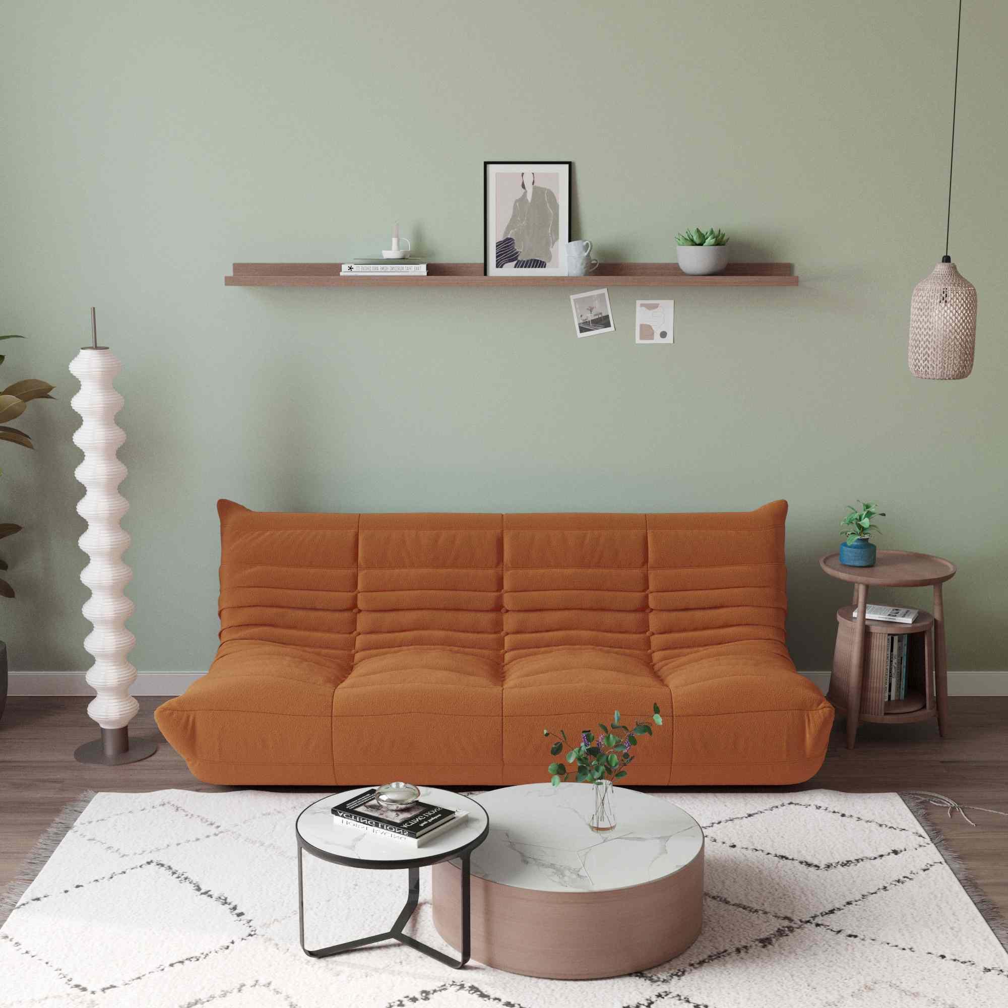 A brown, caterpillar-shaped Togo sofa with a plush texture, situated in a room with minimalist decor, on a patterned rug.
