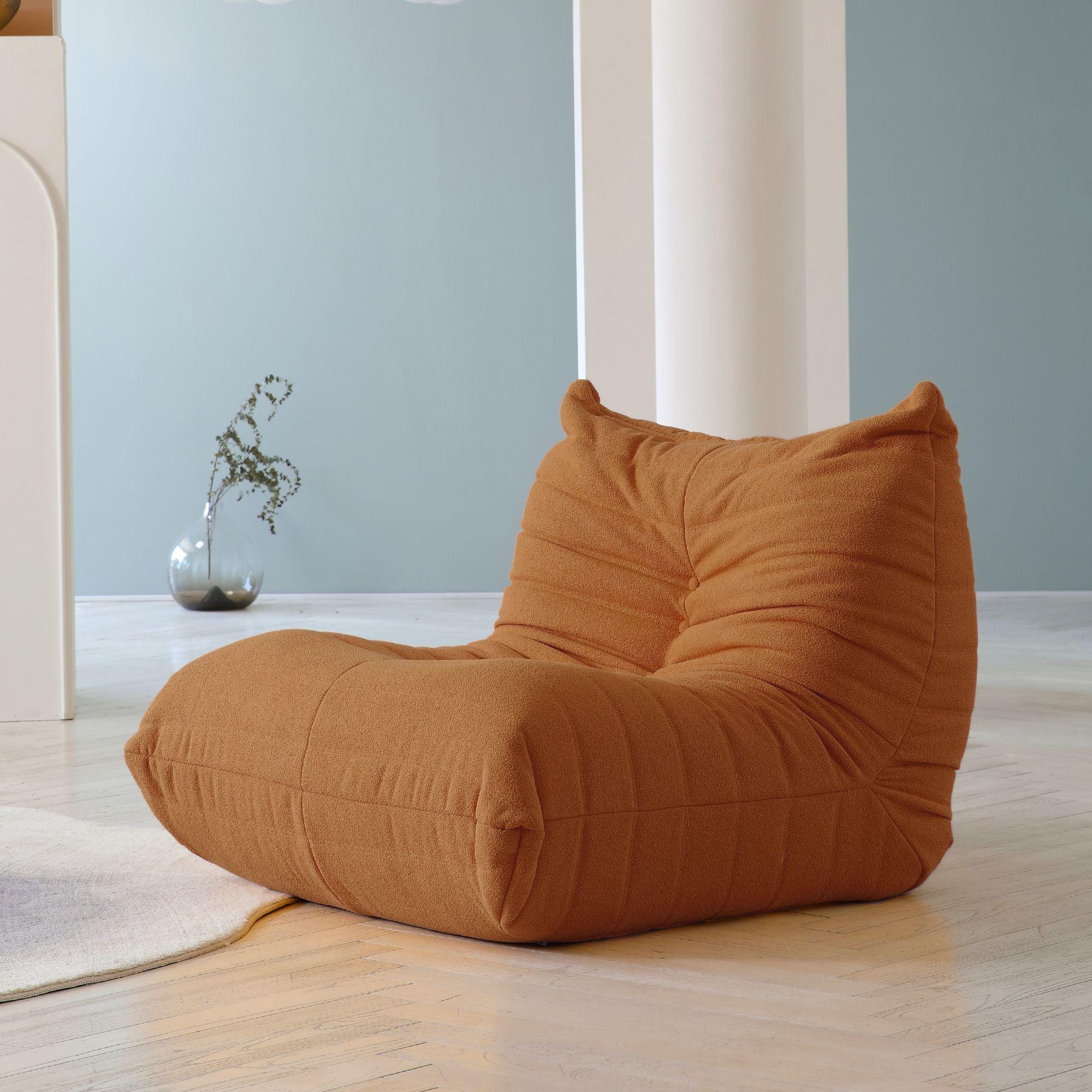 A brown caterpillar-shaped floor armchair placed on a wooden floor in a room with light blue walls.