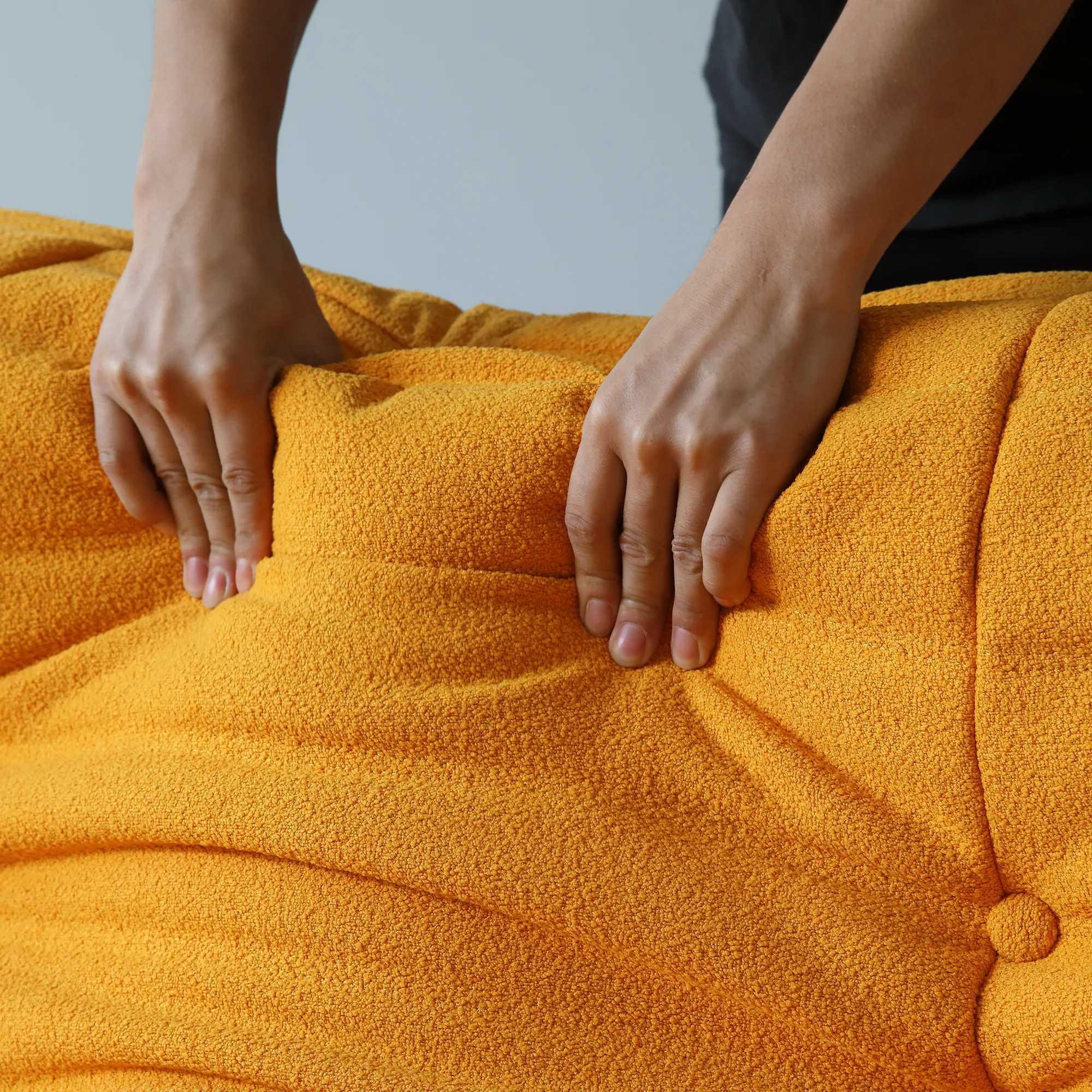 Person pressing on the back of an orange togo sofa to show its softness