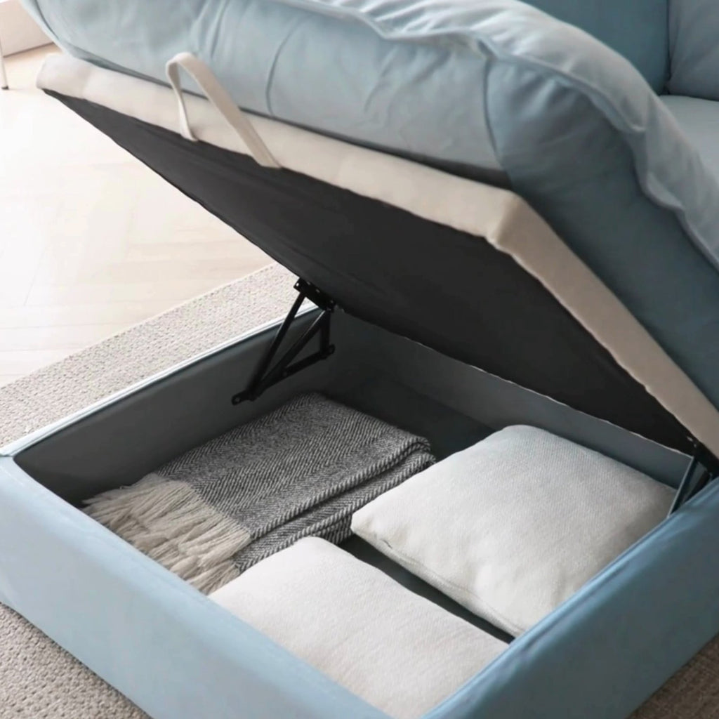 Opened storage ottoman of a baby blue velvet sofa.