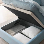 Opened storage ottoman of a baby blue velvet sofa.