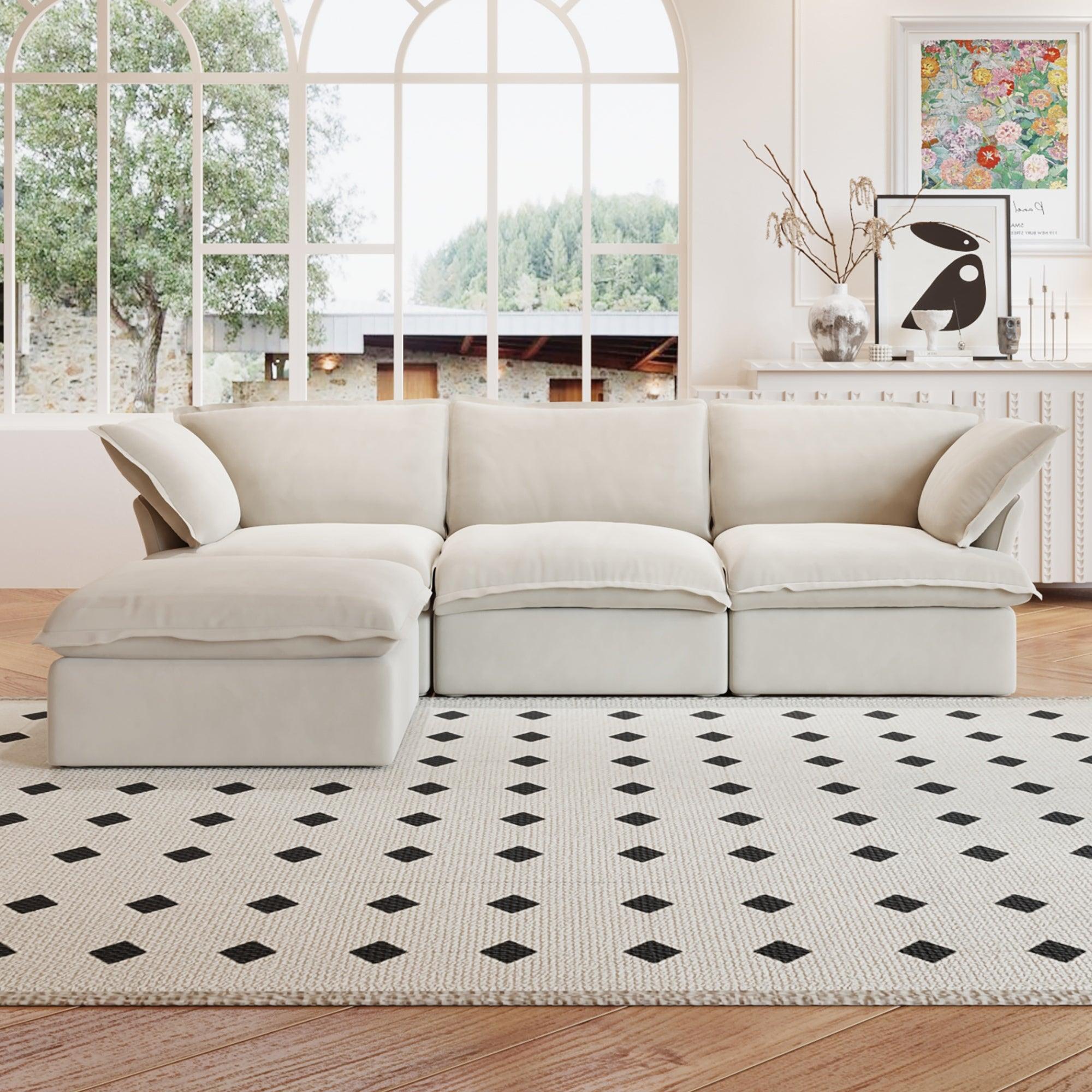 A beige L-shaped linen sectional sofa with a storage ottoman positioned in a bright room with large windows, alongside a patterned rug and in front of a wall with artwork.