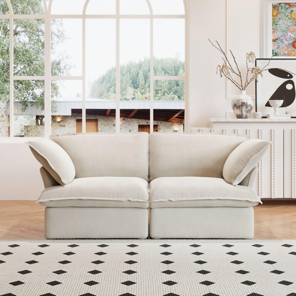 A beige loveseat linen sectional sofa with modular design placed on a patterned rug in a bright living room setting.