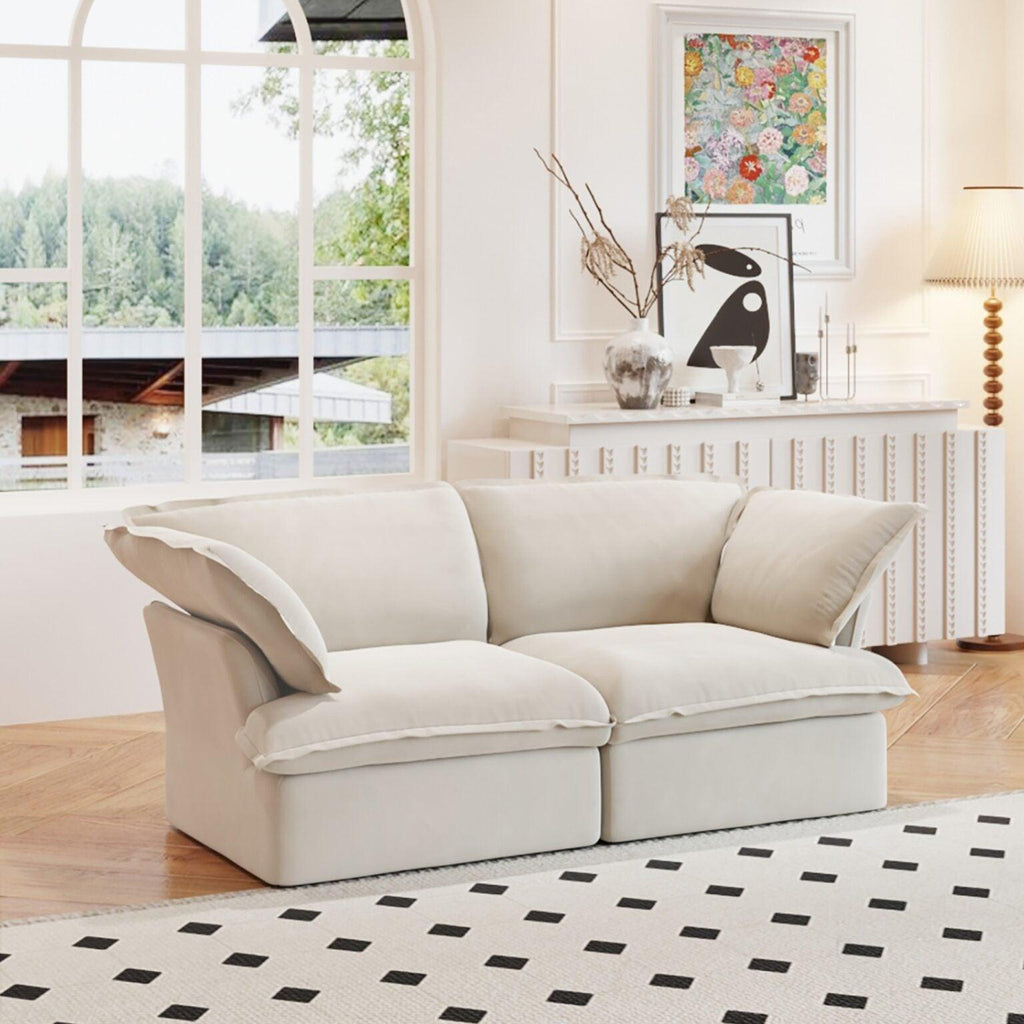 A beige loveseat linen sectional sofa with modular design placed on a patterned rug in a bright living room setting.