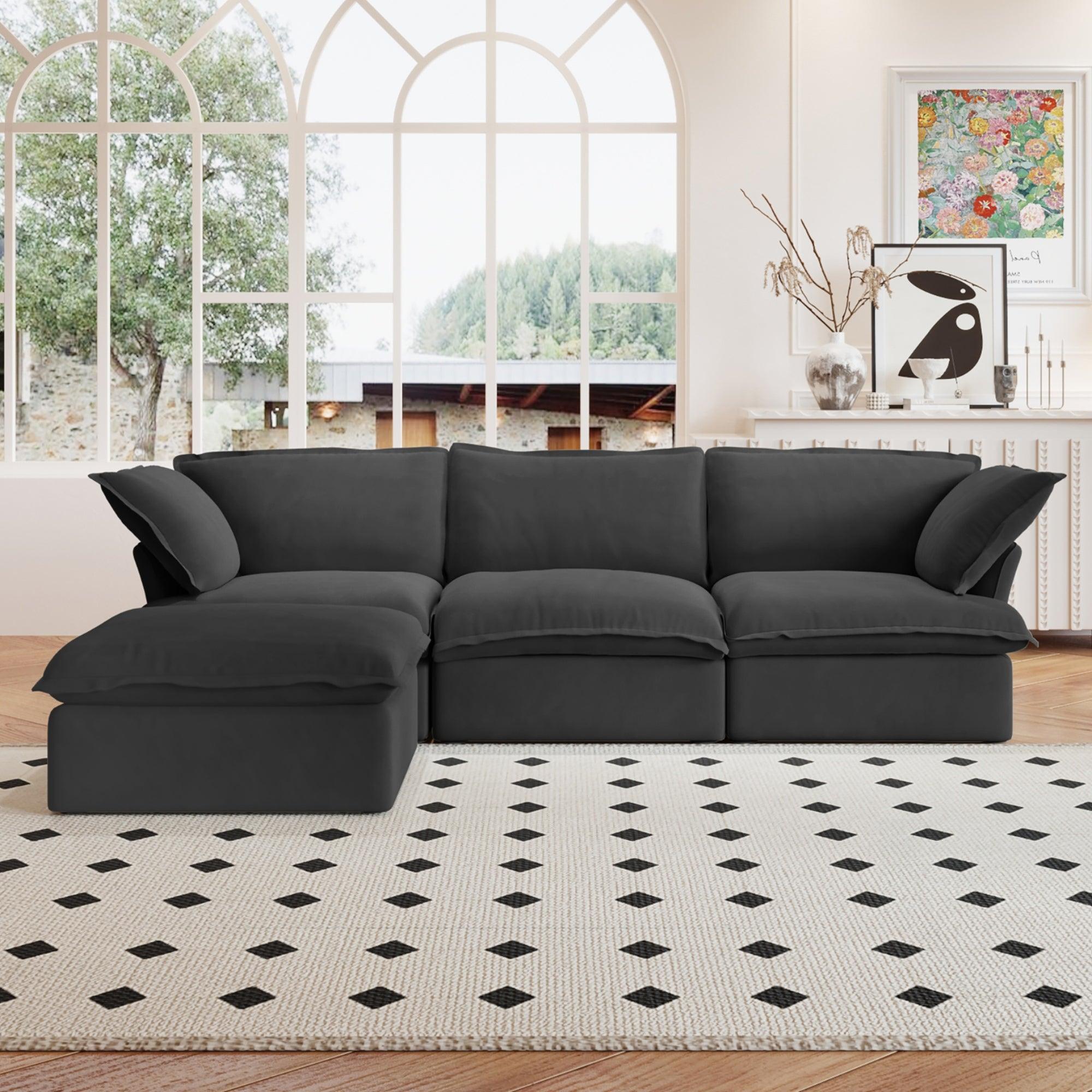 A black L-shaped linen sectional sofa with a storage ottoman positioned in a bright room with large windows, alongside a patterned rug and in front of a wall with artwork.